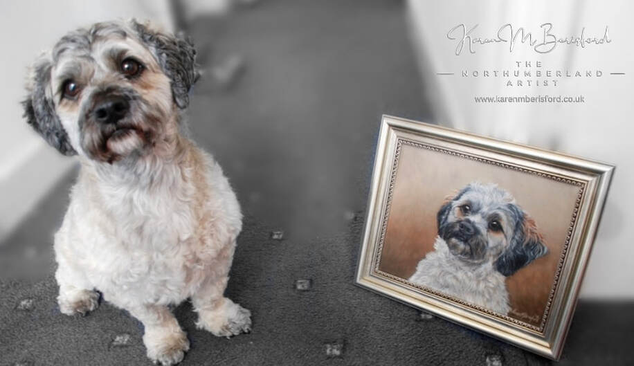 Ernie the Shipoo dog sat next to an acrylic painting of himself. The painting is framed in a gold edged moulding.